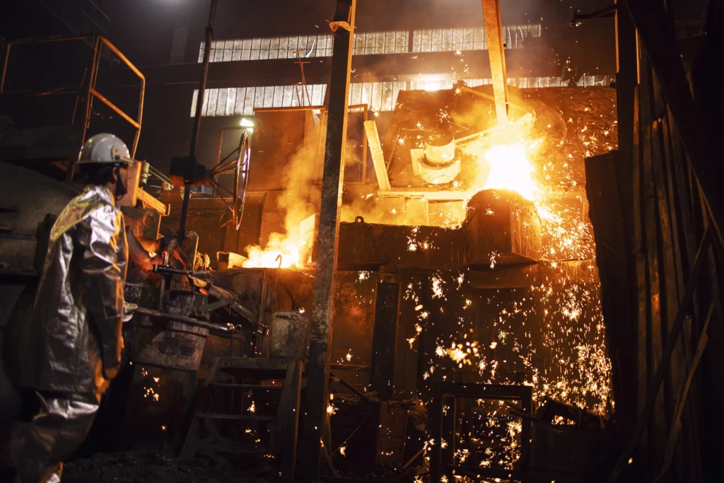 Técnico en taller de metalurgia supervisando proceso de forja.